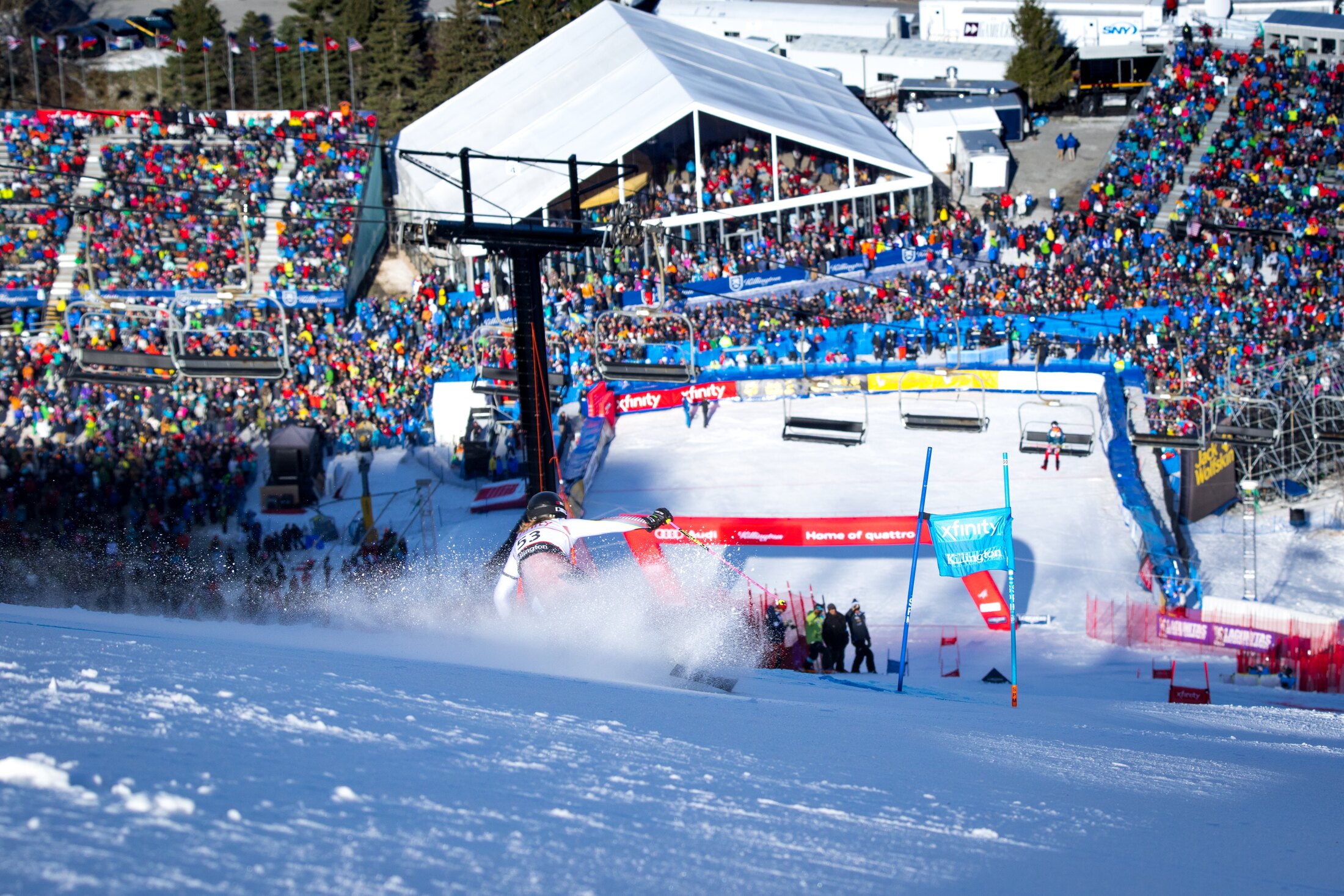 Killington World Cup finish arena — thousands in the stands beneath the mountain, a racer carving the gate