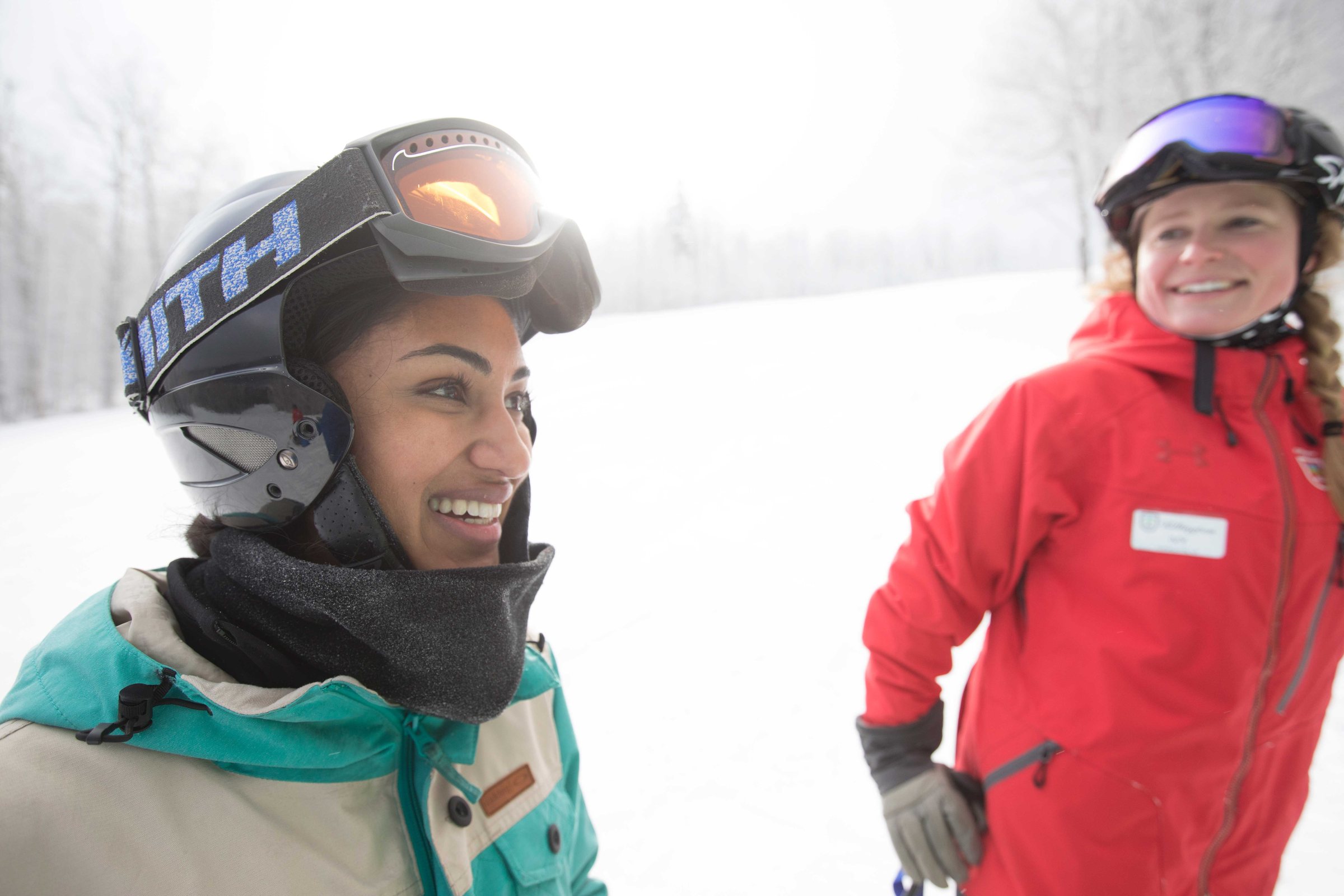 A ski instructor and a guest sharing a laugh on the mountain — the relationship, not the transaction