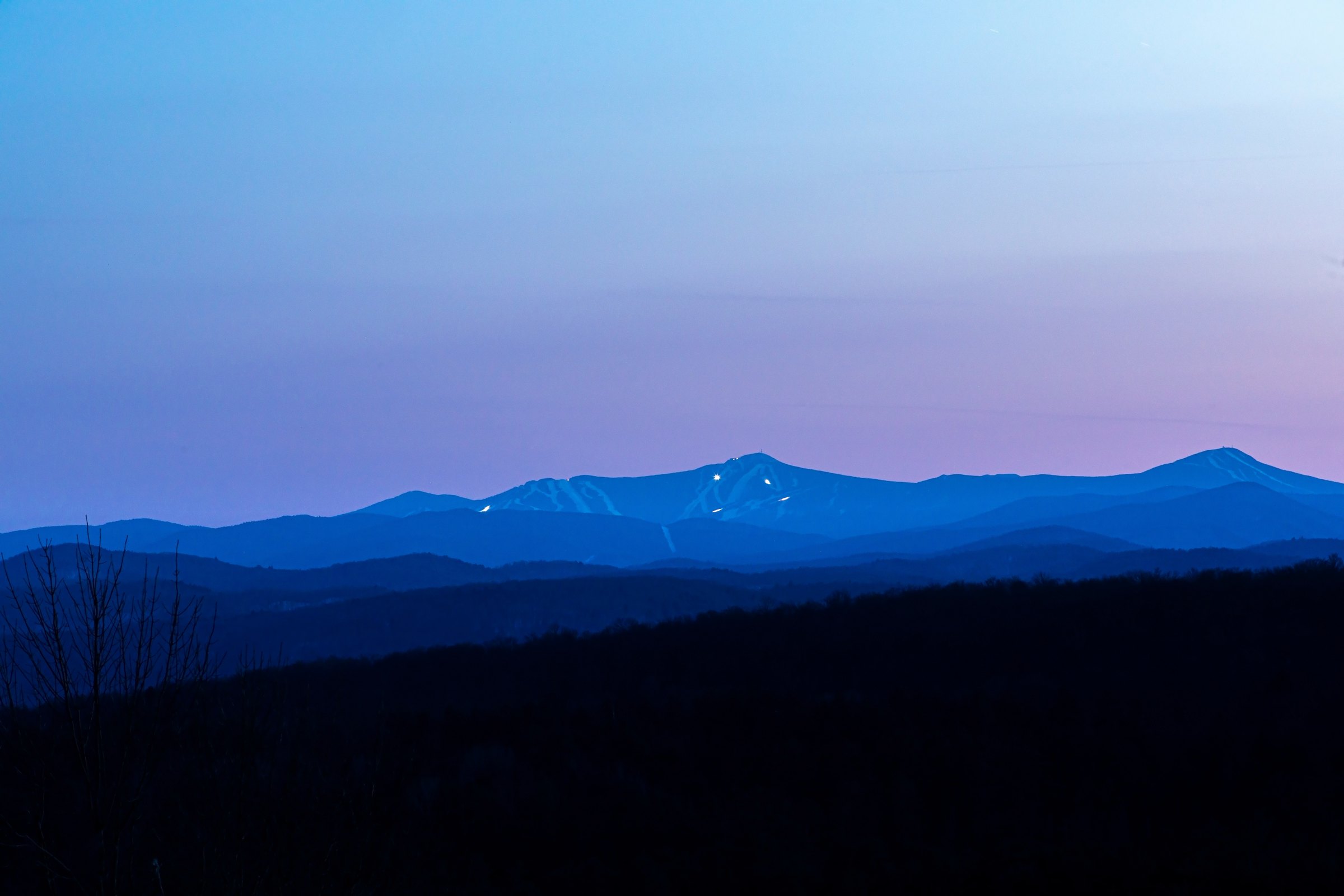 Killington at blue hour — snowcats grooming the trails on Superstar, seen across the valley