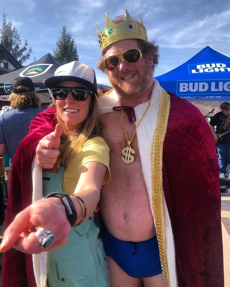 A fan throws an arm around the King in full cape and crown at the Bud Light tent